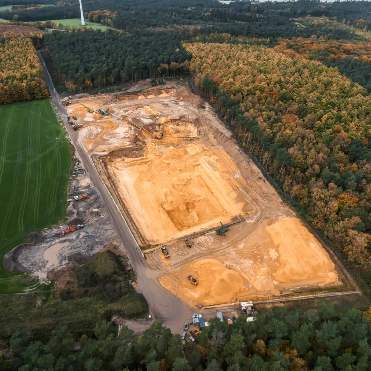 Luftaufnahme der Grube im Herbst, umgeben von Wald und Feldern
